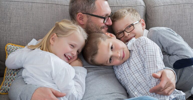 Dad-Embracing-Kids-on-Couch
